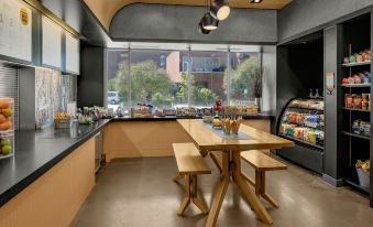 a dining room with a wooden table and chairs , a refrigerator , and a window overlooking the outdoors at Aloft Chapel Hill