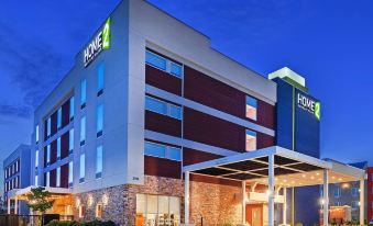 "a large , modern hotel with a green and white sign that reads "" home 2 "". also a parking lot in front of the hotel" at Home2 Suites by Hilton Gonzales