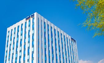 a tall , modern office building with a blue and white exterior , under a clear blue sky at Park Inn by Radisson North Edsa