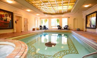 a large indoor swimming pool with a mosaic design in the center , surrounded by lounge chairs and windows at Prince of Wales