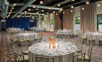 a large , round table with white tablecloth and silver chairs is set up for an event in a room with blue curtains at Hotel Nyack, A Joie de Vivre Hotel by Hyatt