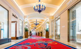 "a red carpeted hallway with blue chandeliers and potted plants , leading to a store named "" the birdcage ""." at Grand Hyatt Baha Mar