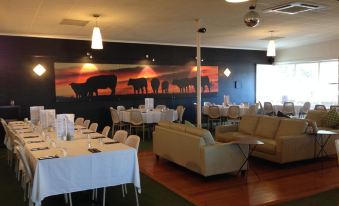 a dining room with white tables and chairs , and a large mural on the wall at Riverfront Motel & Villas
