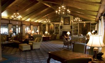 a large room with wooden furniture , including chairs , a couch , and a dining table , as well as a fireplace at Pine Needles Lodge & Golf Club