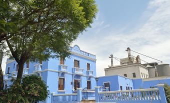 a blue building with white trim , surrounded by trees and a white fence , under a clear blue sky at Las Mercedes