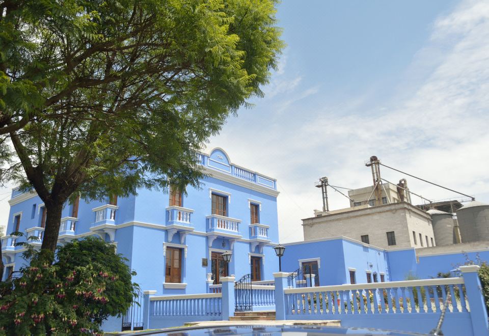 a blue building with a white fence in front of it , surrounded by trees and other buildings at Las Mercedes