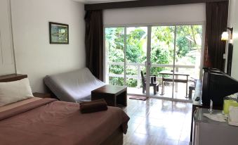 a bedroom with a bed , a chair , and a sliding glass door leading to a patio at Chanthaburi Garden Hotel