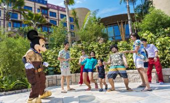 A family and their friends pose for pictures in front of a theme park at Disney Explorers Lodge