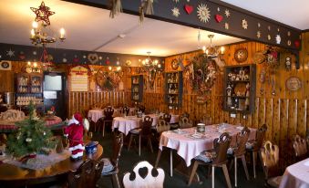 a large , well - decorated dining room with multiple tables and chairs , decorated with christmas decorations on the walls at Karelia Alpine Lodge