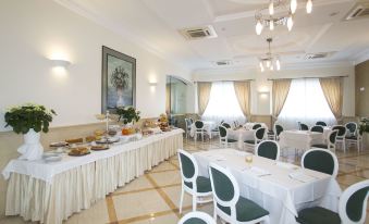 a large dining room with white tablecloths , chairs , and a buffet table filled with various food items at Hotel Cavaliere