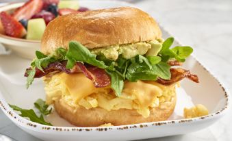 a delicious breakfast sandwich on a white plate , accompanied by a fork and a knife at Courtyard Schenectady at Mohawk Harbor