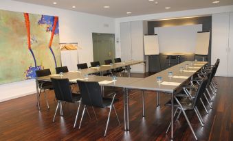 a conference room with a long table , chairs , and a whiteboard , set up for a meeting at The Ambassador