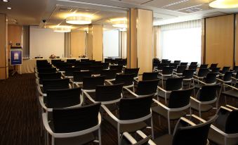 a conference room with rows of black chairs arranged in a semicircle , and a podium at the front of the room at Invisa Hotel la Cala