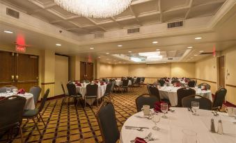 a large , well - lit conference room with multiple tables set for a formal event , white tablecloths , and chandeliers at Four Points by Sheraton Allentown Lehigh Valley