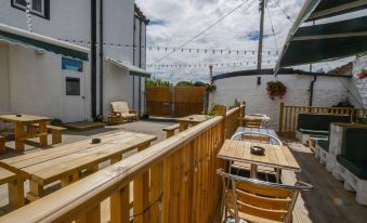 a wooden deck with tables and chairs , as well as a sign for a restaurant at New Inn Hotel