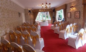 a room with white chairs and gold bows on the floor is set up for a wedding ceremony at Woodlands Hotel