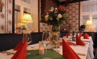 a table is set with wine glasses , flowers , and napkins for a formal dinner in a restaurant at Hotel Berg