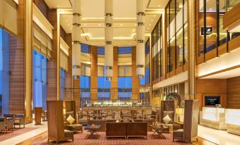 a modern hotel lobby with large windows , wooden paneling , and multiple seating areas , giving it an elegant and luxurious atmosphere at Courtyard Ahmedabad