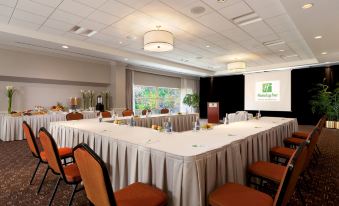 a large conference room with multiple tables and chairs , a projector screen , and a green plant at Holiday Inn Laval - Montreal