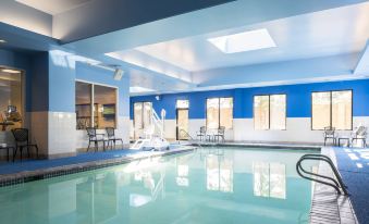 a large , well - maintained swimming pool with blue and white walls , surrounded by chairs and tables at Courtyard Seattle Federal Way