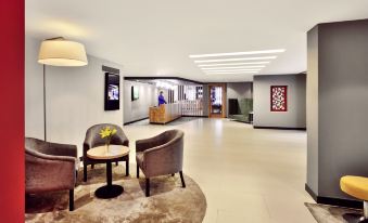 a modern hotel lobby with various seating options , including couches and chairs , as well as a reception desk at Park Inn by Radisson New Delhi Lajpat Nagar
