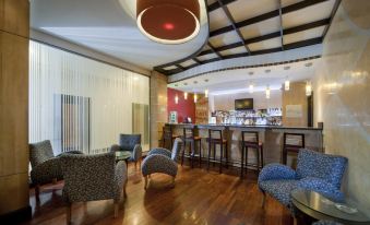 a modern bar area with wooden floors , several chairs , and a dining table in the background at Hodelpa Garden Court