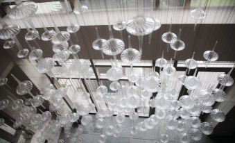 a large , clear chandelier made of clear plastic cups hanging from the ceiling of a building at Micasa Hotel