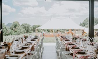 a large outdoor event space with a white tent and several tables set up for guests at Ardeena
