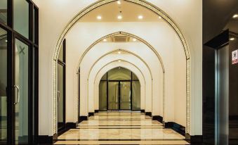 a long hallway with a checkered floor and white walls , featuring an arched ceiling with lights at Alfahad Hotel