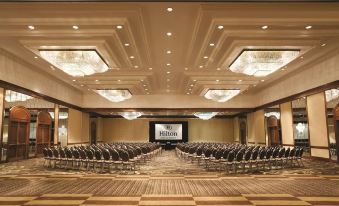 a large conference room with rows of chairs arranged in a semicircle , and a projector screen mounted on the wall at Hilton Memphis