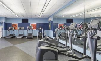 a well - equipped gym with various exercise equipment , including treadmills and weight machines , set against a blue wall at Four Points by Sheraton Chicago O'Hare