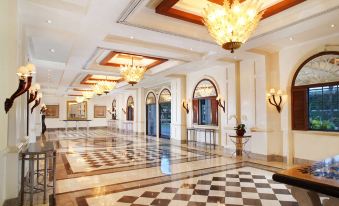 a large , ornate hotel lobby with high ceilings , chandeliers , and marble floors , as well as a reception desk and a staircase at Melia Purosani Yogyakarta