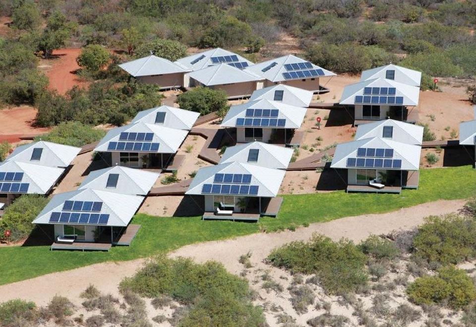aerial view of a group of solar panels on a building surrounded by trees and grass at Eco Beach Wilderness Retreat