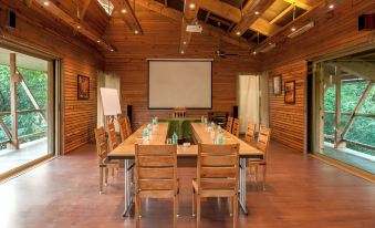 a large conference room with wooden walls , a projector screen , and multiple tables set up for meetings at The Machan