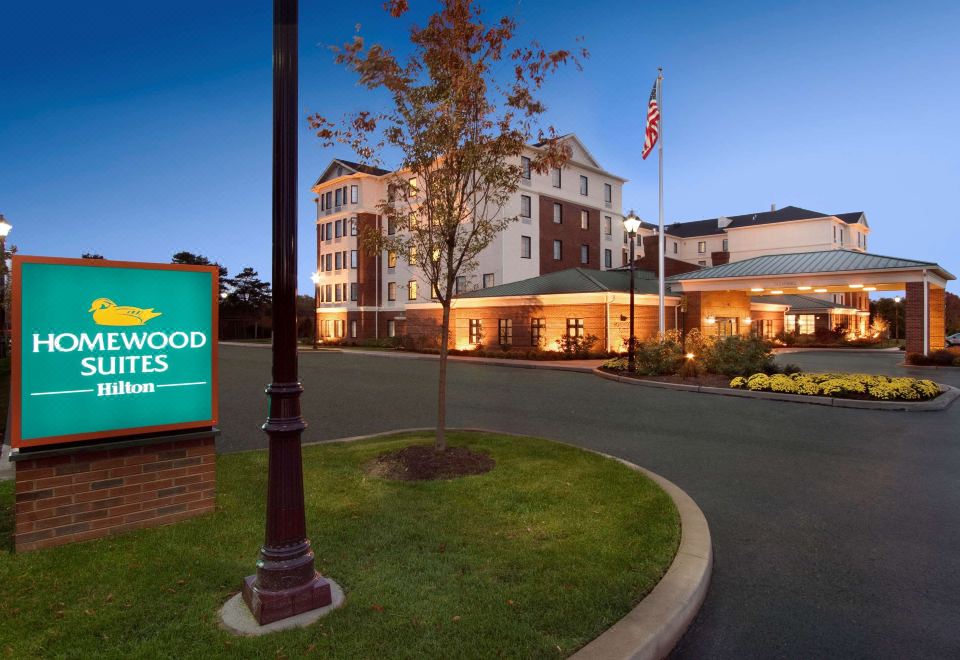 "a large hotel with a sign that says "" meadowbrook place "" and an american flag in front" at Homewood Suites by Hilton Newtown - Langhorne