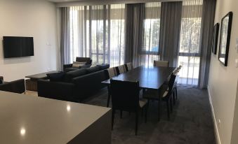 a spacious living room with a large dining table and chairs , as well as a kitchen area at Knightsbridge Canberra