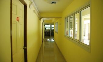 a hallway with a yellow wall and floor , a light at the end , and large windows at Sirasit 999 Mansion