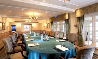a conference room with a large table covered in a blue tablecloth , surrounded by chairs at Macdonald Compleat Angler