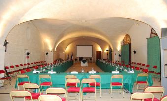 a long conference table with green and red tablecloths , gold chairs , and a projector screen at Chateau de la Bourdaisiere