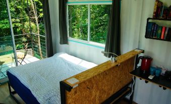 a bed with a wooden headboard is situated next to a window in a room at Sarang by the Brook