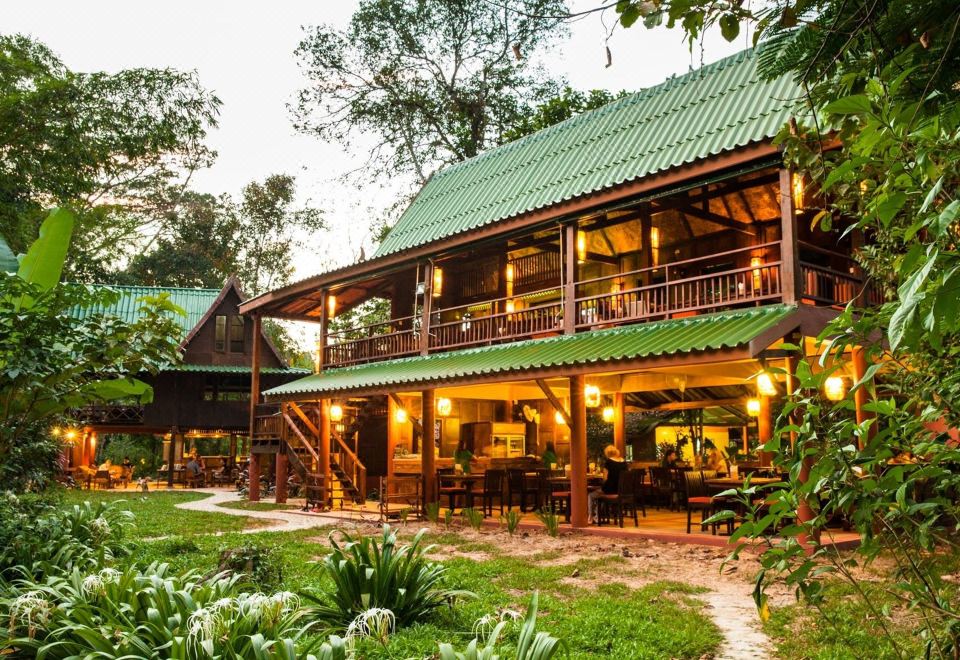 a large wooden house surrounded by trees , with a patio and a fire pit in the backyard at Our Jungle House