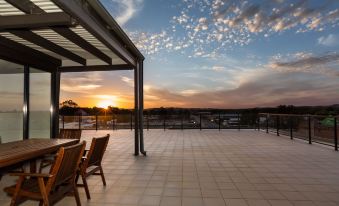 a balcony overlooking a beautiful sunset , with two chairs placed on the balcony for relaxation at The Penthouse
