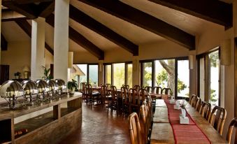 A restaurant with spacious windows and tables in the center, accompanied by an outdoor dining area at Haatiban Resort