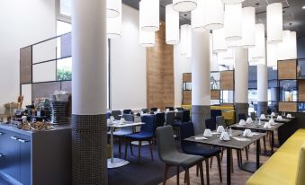a modern , well - lit dining area with multiple tables and chairs arranged for a group of people at Novotel Chateau de Versailles