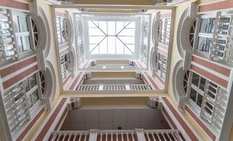 a grand staircase with red and white railings , leading to a skylight in the center at Hotel Inglaterra