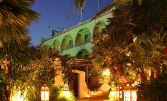 a hotel with a large balcony and palm trees , surrounded by lit up lights and lanterns at Hotel Simius Playa