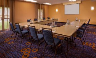 a conference room with a long table , chairs , and a screen , set up for a meeting or presentation at Courtyard Richmond West