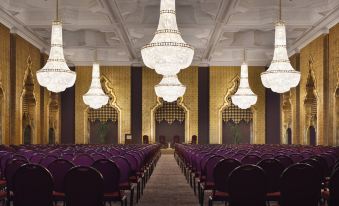 a large , well - lit conference room with purple chairs and white chandeliers hanging from the ceiling at Marriott Mena House, Cairo