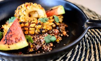 a black bowl filled with corn on the cob and watermelon slices , surrounded by a variety of spices at Riviera Marriott Hotel la Porte de Monaco