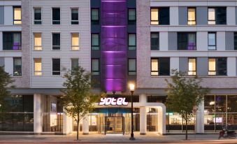 "a tall building with a purple sign that says "" soal "" is surrounded by trees and has a sidewalk in front" at Yotel Boston